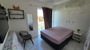 a bedroom with a bed and a chair and a window at Jacumã Gold in Conde