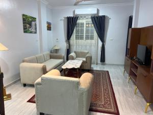 a living room with chairs and a table and a tv at Spacious Luxury Nile-View Apartment on Upper Floor with Rooftop, Jacuzzi & BBQ ,Steps from Hilton Hotel in Luxor
