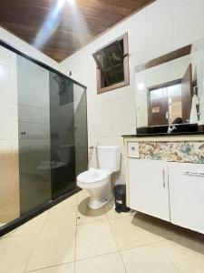 a bathroom with a toilet and a glass shower at Apartamento Rangel in Cairu
