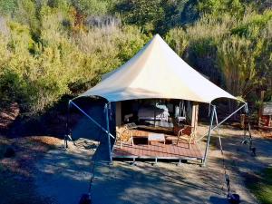 a white tent with a chair in a field at Ukiyo Nature Retreat in Fingal +7 photos