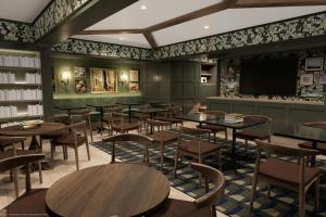 a restaurant with tables and chairs and a flat screen tv at The Queen’s Cue, Stratford, A Tribute Portfolio Hotel in Stratford