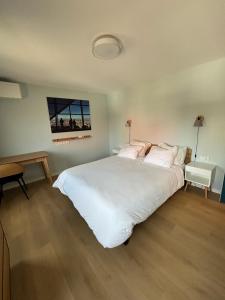 ein Schlafzimmer mit einem großen weißen Bett und einem Schreibtisch in der Unterkunft MaaSang in Maasbree
