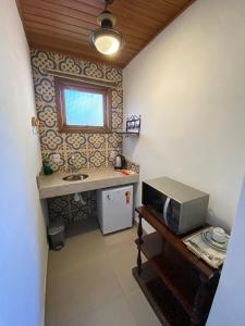 a small kitchen with a microwave on a table at Na Trilha da Ostra 2 - Brechó e Antiquário in Brumadinho