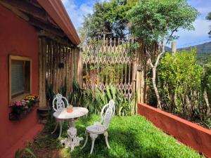 a patio with two chairs and a table and a fence at Na Trilha da Ostra 2 - Brechó e Antiquário in Brumadinho