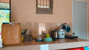a kitchen counter with a sink and a tea kettle at Macabuag Apartment in Narra +10 photos