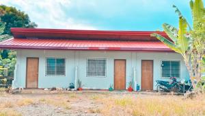 a house with a motorcycle parked in front of it at Macabuag Apartment in Narra