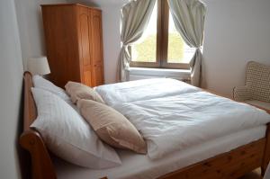 a bed with white sheets and pillows in front of a window at Vila Adalbert in Liberec