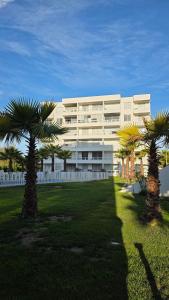 a large white building with palm trees in front of it at Apartment steps away from the beach in La Serena