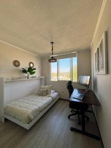 a bedroom with a bed and a desk and a laptop at Apartment steps away from the beach in La Serena +30 photos