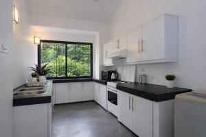 a kitchen with white cabinets and a large window at 519@jamtree in Colombo