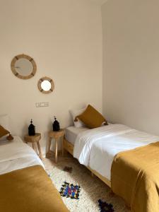 a bedroom with two beds and a mirror on the wall at Tamonda in Tamraght Ouzdar