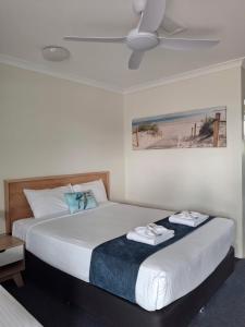 a bedroom with two beds and a ceiling fan at Hervey Bay Motel in Hervey Bay +87 photos