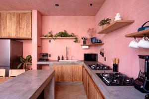 a kitchen with pink walls and wooden cabinets at Amplitude Coliving in Brisas de Zicatela