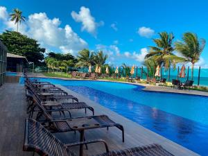 a row of chairs sitting next to a swimming pool at Flat Gold Sea View - Tabatinga Beach in Conde