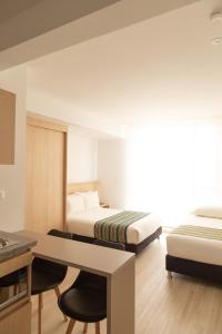 a hotel room with two beds and a desk at Hotel Estar in Manizales