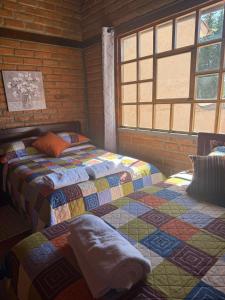 two beds in a room with two windows at Casa acogedora y espaciosa in Huamboya
