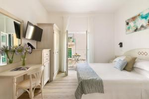 a white bedroom with a desk and a bed at Hotel Week End in Porto Santo Stefano
