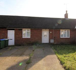 a red brick house with two white garage doors at Joni Bungalow-2-Bedroom HOME in Slades Green
