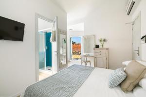 a white bedroom with a bed and a balcony at Hotel Week End in Porto Santo Stefano