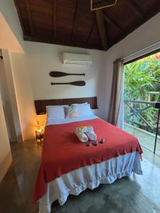 a bedroom with a red bed with two stuffed animals on it at Casa Recanto das arvores in Itacaré