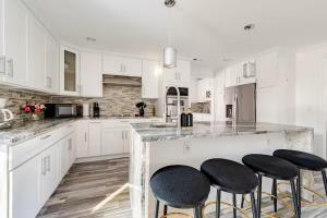 a white kitchen with white cabinets and black stools at Norwalk Retreat in Norwalk