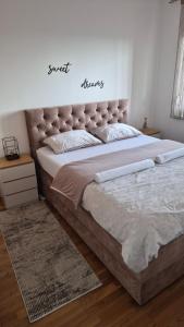 a bedroom with a large bed with a padded headboard at Apartman River - stan na dan Gradiška in Bosanska Gradiška