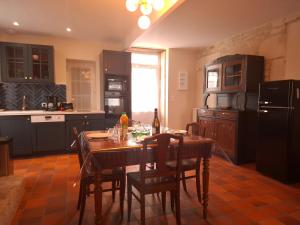 a kitchen with a table with chairs and a refrigerator at La Glycine, Maison au calme avec jardin, Fibre Wi-Fi, 20 min des plages, Parking privé in Luçon