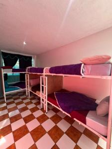 a room with three bunk beds and a checkered floor at Nawal Hostel in Santa Cruz La Laguna
