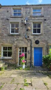 a stone house with a blue door and flowers at Ground floor, Very central, 2 Bed - Cobbles Apartment in Buxton