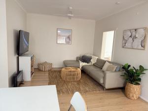 a living room with a couch and a tv at Stunning Ground Floor Apt with Ocean Views in Cronulla