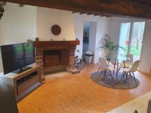 a living room with a dining table and a fireplace at Gîte Les Fourmilières in Ligny-le-Ribault