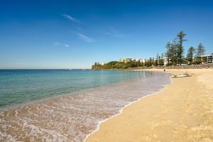 a beach with people and the ocean on a sunny day at Moffat Beach Entertainer with Kids Retreat & Walk to Beach in Caloundra
