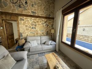a living room with a couch and a stone wall at Casa Rural Belladona in Valdeprados