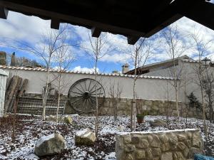 a garden with a waterwheel and trees in the snow at Casa Rural Belladona in Valdeprados