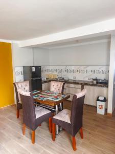 a dining room with a table and chairs and a kitchen at Residencial SKD in Puno