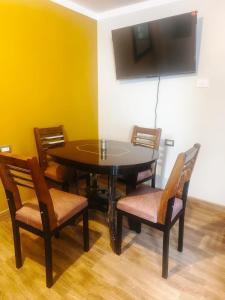 a dining room with a table with chairs and a television at Residencial SKD in Puno +5 photos