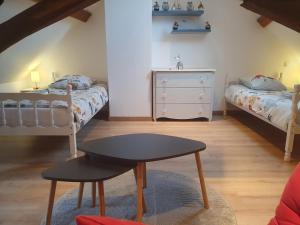 a bedroom with two beds and a table and a stool at Gîte Les Fourmilières in Ligny-le-Ribault