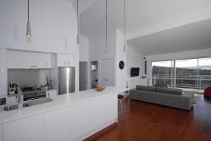 a white kitchen and living room with a couch at Wharau Lodge in Kerikeri