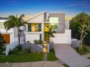 a white house with palm trees in front of it at Luxe on North Point in Kingscliff