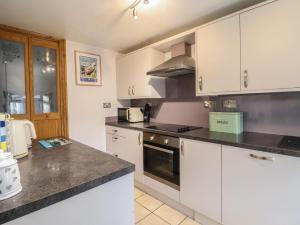 a kitchen with white cabinets and a stove top oven at Old Station Cottage in Blaenau-Ffestiniog +29 photos