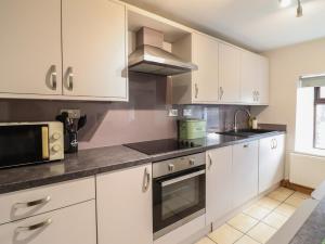 a kitchen with white cabinets and a microwave at Old Station Cottage in Blaenau-Ffestiniog