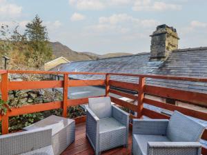 a deck with two chairs and a roof at Old Station Cottage in Blaenau-Ffestiniog