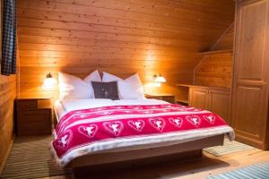 a bedroom with a large bed with a red blanket at Ferienhütte Windlegern in Neukirchen +5 photos