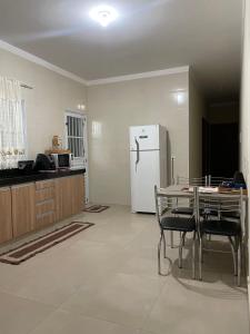a kitchen with a table and a white refrigerator at Recanto dos Ipês a 4 min do Moinho in Holambra
