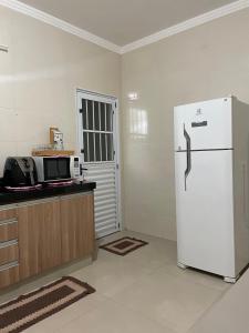 a kitchen with a white refrigerator and a microwave at Recanto dos Ipês a 4 min do Moinho in Holambra +10 photos