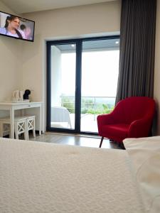 a hotel room with a red chair and a window at Quinta do Botas in Moimenta