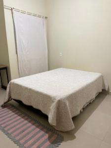 a bed with a white bedspread on it in a room at Recanto dos Ipês a 4 min do Moinho in Holambra