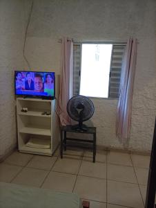a living room with a television and a fan at Sol & mar Hospedagem - Boqueirão Sul Via Balsa Cananéia in Ilha Comprida