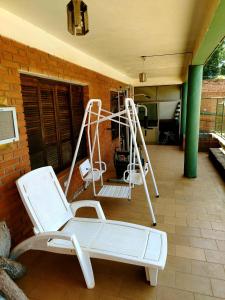a porch with two white chairs and a swing at Posada Familiar ELDORADO in Eldorado +56 photos