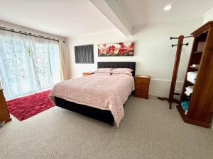 a bedroom with a large bed and a window at Cosy Raglan Studio - Walk to Beach and Village - Roberts St - Studio Downstairs in Raglan